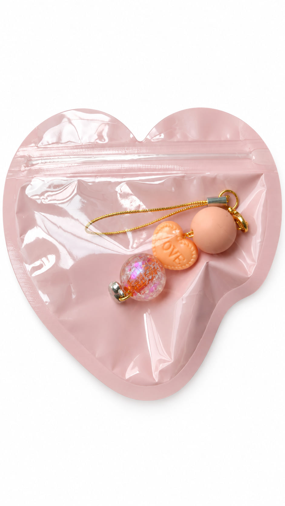 A close-up studio photograph of a handmade beaded phone strap keychain presented inside a protective, translucent pastel pink heart-shaped zip-lock packaging pouch against a crisp white backdrop.