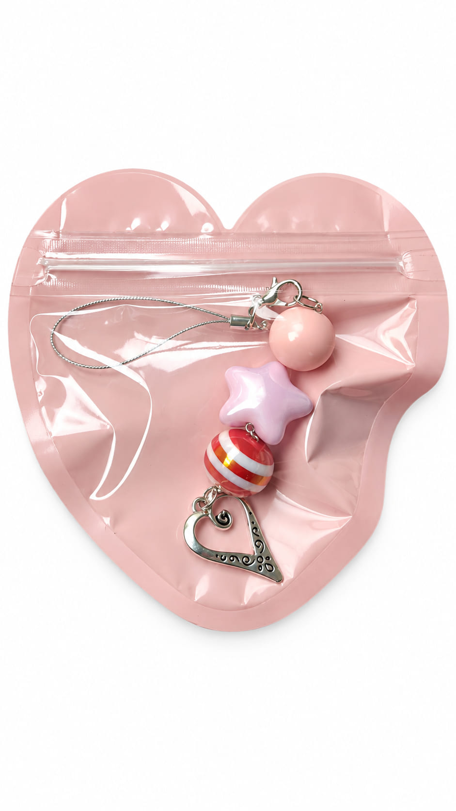 A close-up studio photograph of a handmade beaded phone strap keychain presented inside a protective, translucent pastel pink heart-shaped zip-lock packaging pouch against a crisp white backdrop.