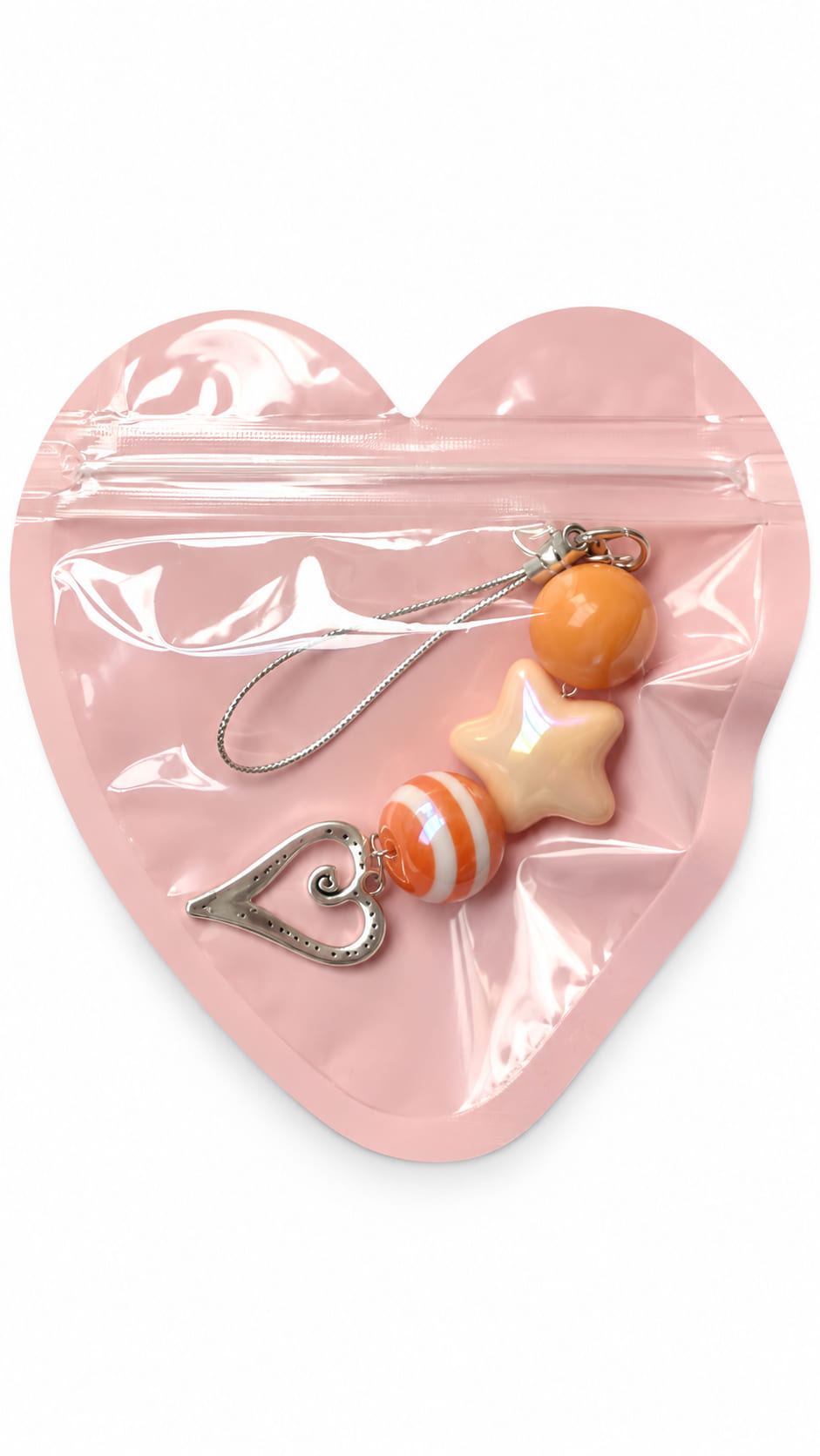 A close-up studio photograph of a handmade beaded phone strap keychain presented inside a protective, translucent pastel pink heart-shaped zip-lock packaging pouch against a crisp white backdrop.