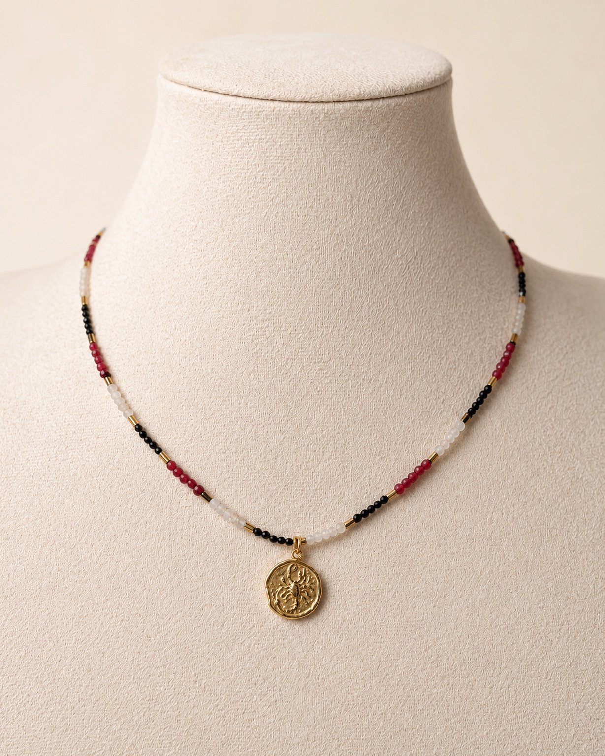 Collana Scorpione in pietre naturali con pendente dorato esposta su manichino.
