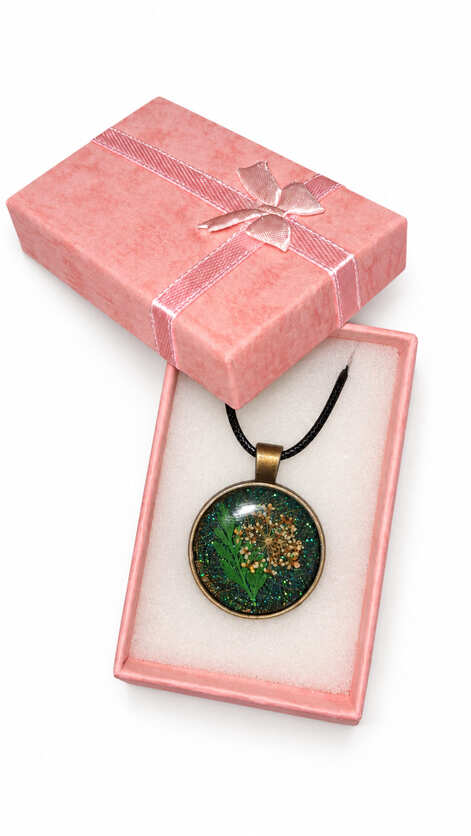 Green botanical pressed flower resin necklace presented in pink gift box