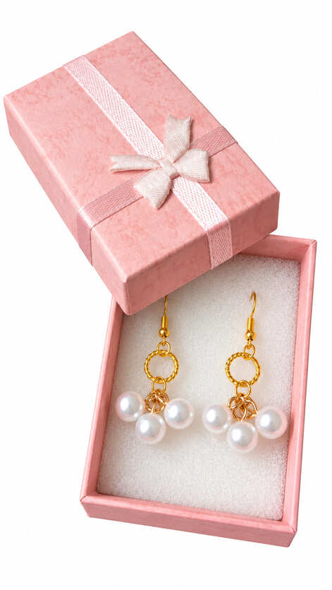 Luxury 18ct gold plated pearl drop earrings presented inside an open signature textured pink gift box with a satin ribbon bow.