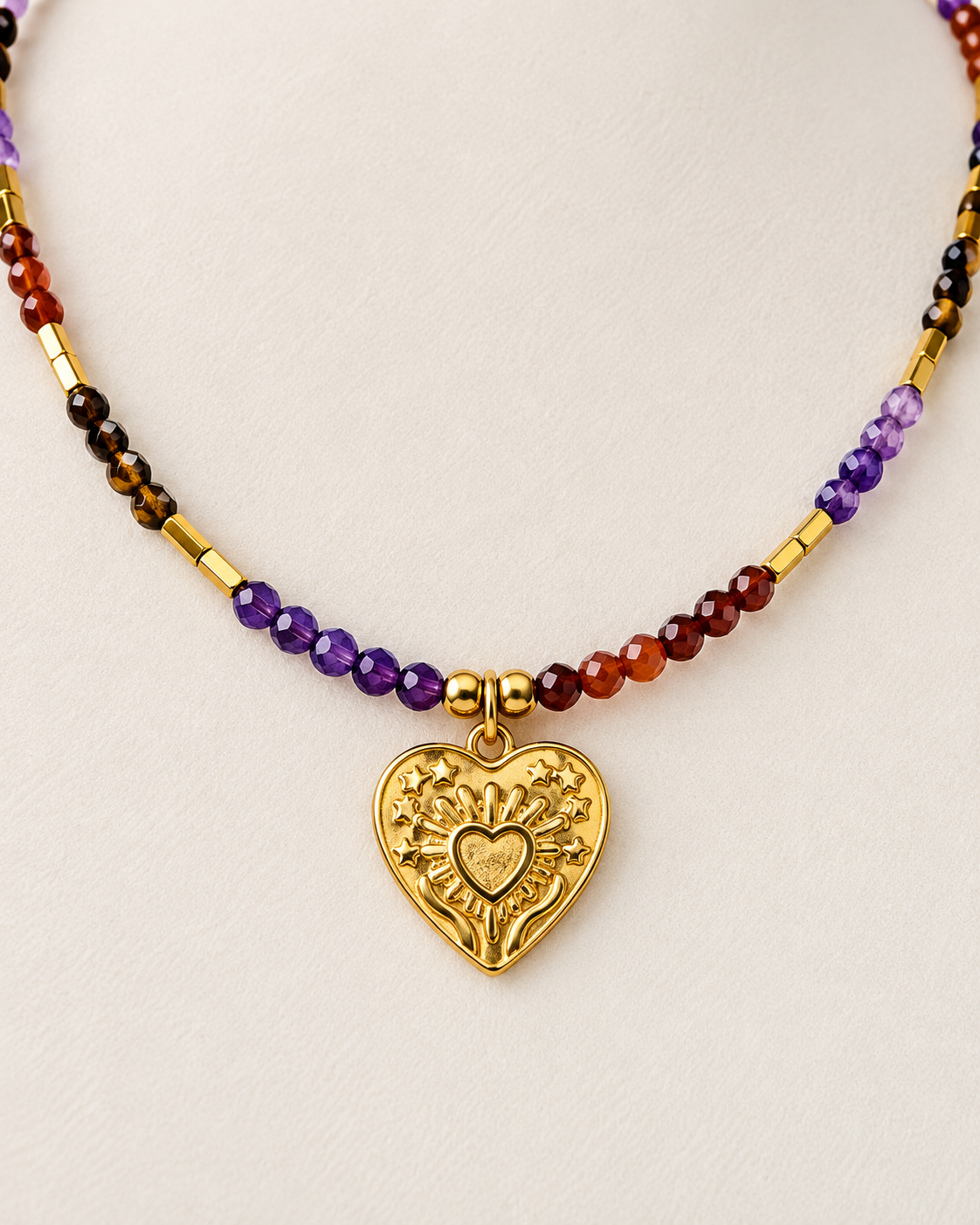 Dettaglio collana Cuore in Mano con granato rosso ametista occhio di tigre e finiture dorate