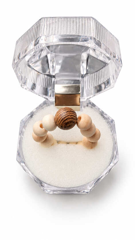 Handmade natural wooden bead stretch ring displayed in a clear jewellery gift box with pale wood beads and a dark wood-grain focal bead.