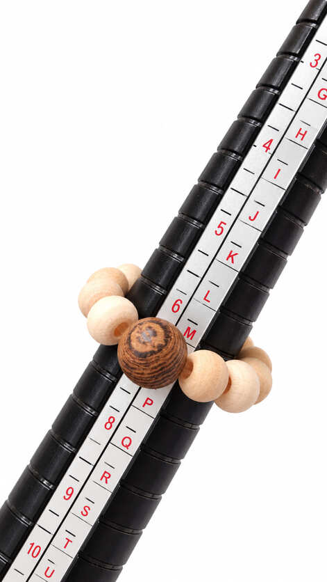 Handmade wooden bead stretch ring shown on a ring sizing mandrel at approximately UK size M and US size 6.