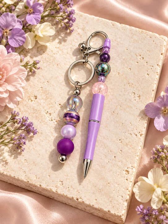 Handmade purple beaded pen and matching keychain with lilac and iridescent beads on floral background