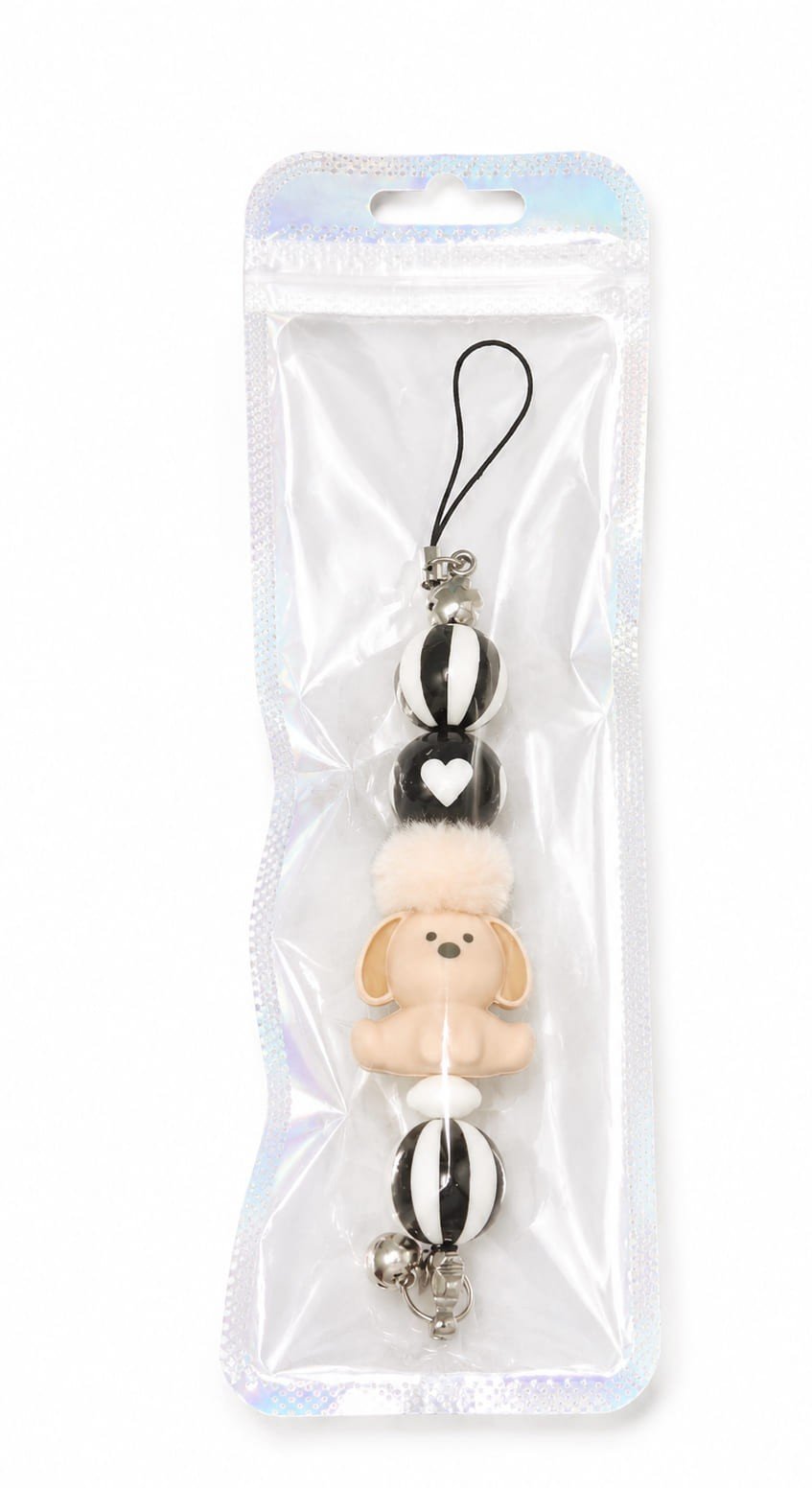 Handmade black and white puppy dog beaded phone charm with fluffy pom-pom and silver heart charm in holographic packaging.