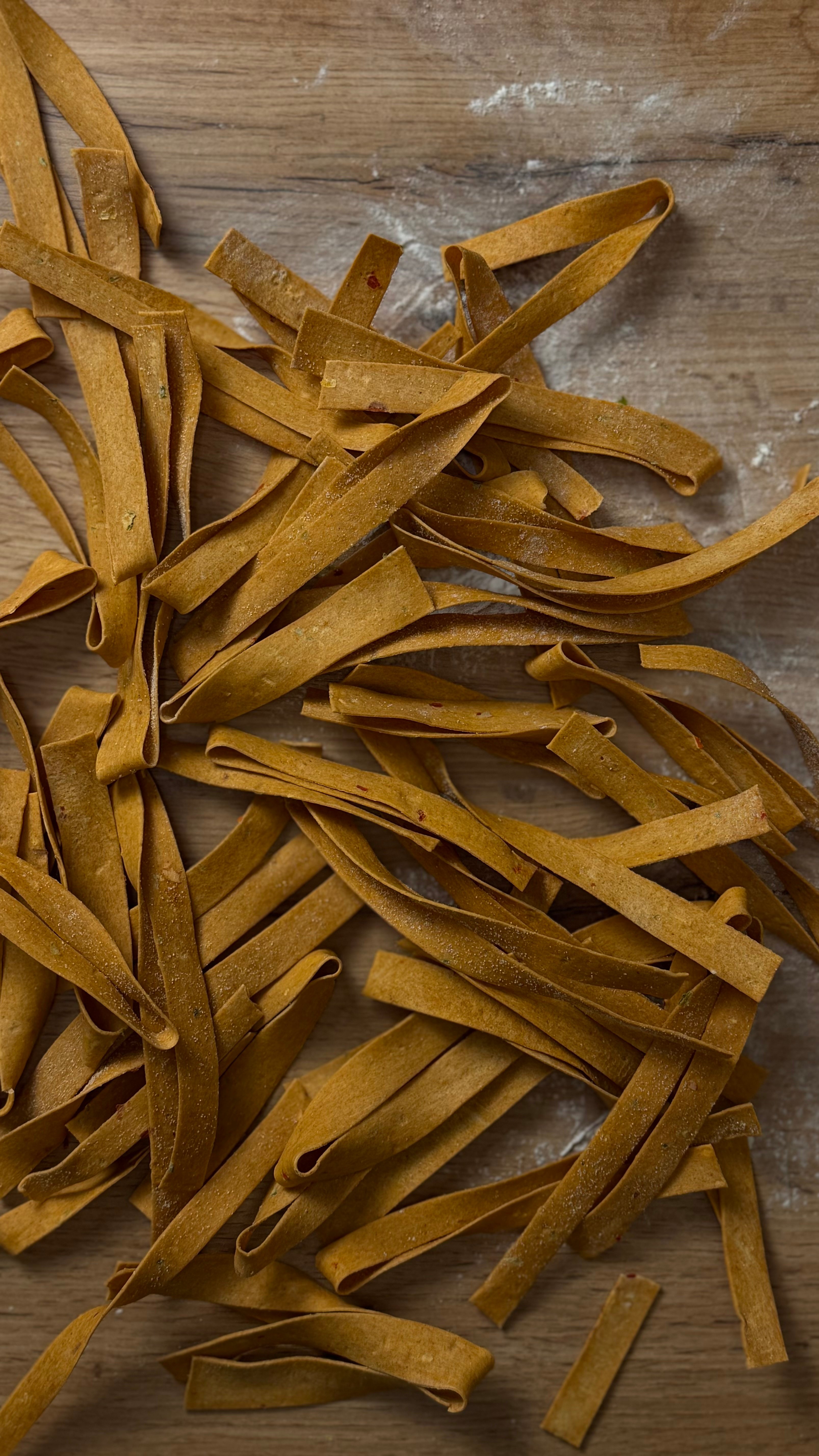 Selbstgemachte Chili-Nudeln / Pasta, getrocknet und auf einem Holztisch ausgelegt.