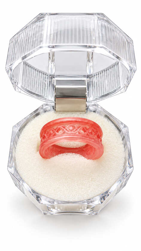 Handmade coral pink epoxy resin ring with raised interwoven knot design displayed in a clear faceted jewellery box.