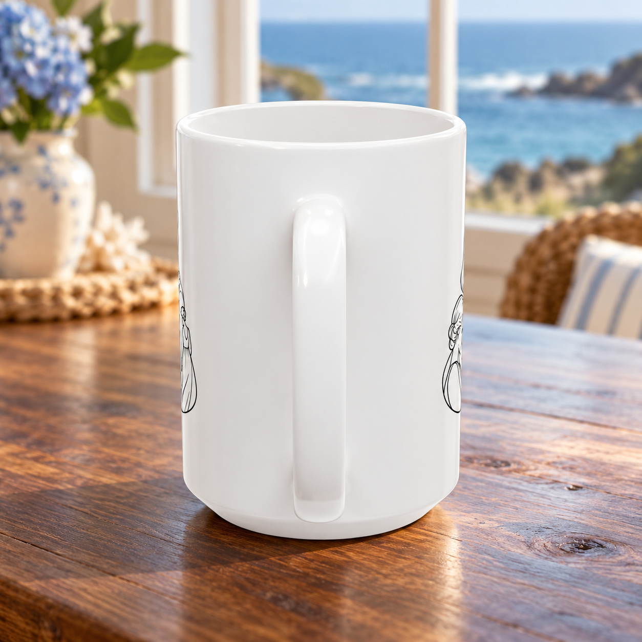 Handle-side view of the white ceramic mug on a wooden table beside flowers and a window overlooking the water.